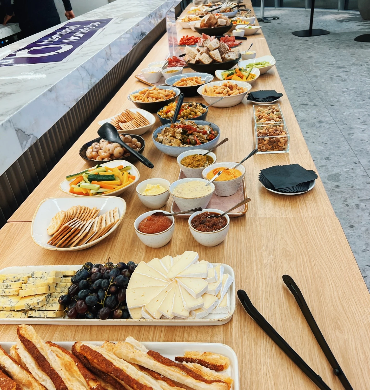 Buffet table arranged with cheeses, bread, dips, crudités, crackers, fruit and savoury snacks