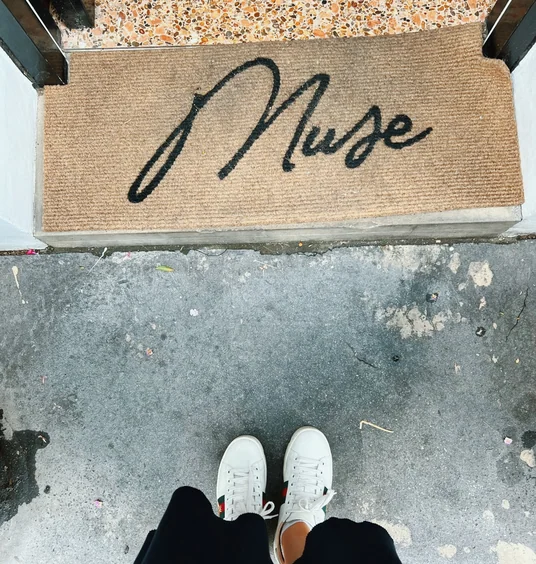 A doormat reading Welcome outside a doorway, with white trainers visible below