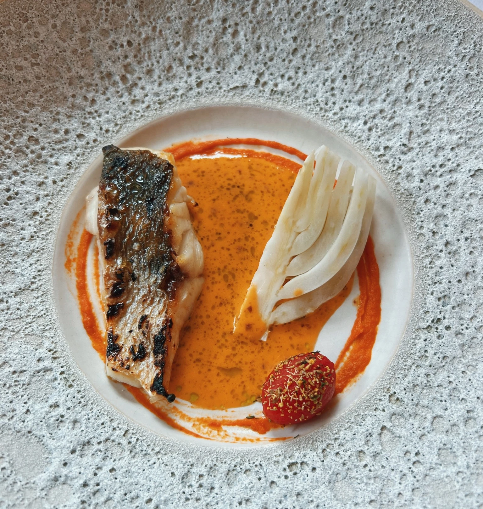 Grilled fish served with fennel, red pepper sauce and a red vegetable garnish