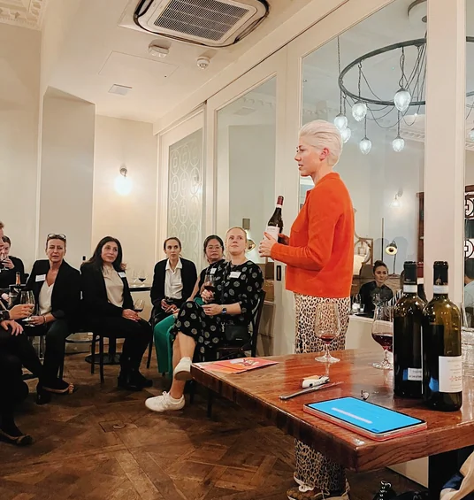 Wine presenter speaking to a seated group in a stylish indoor tasting venue