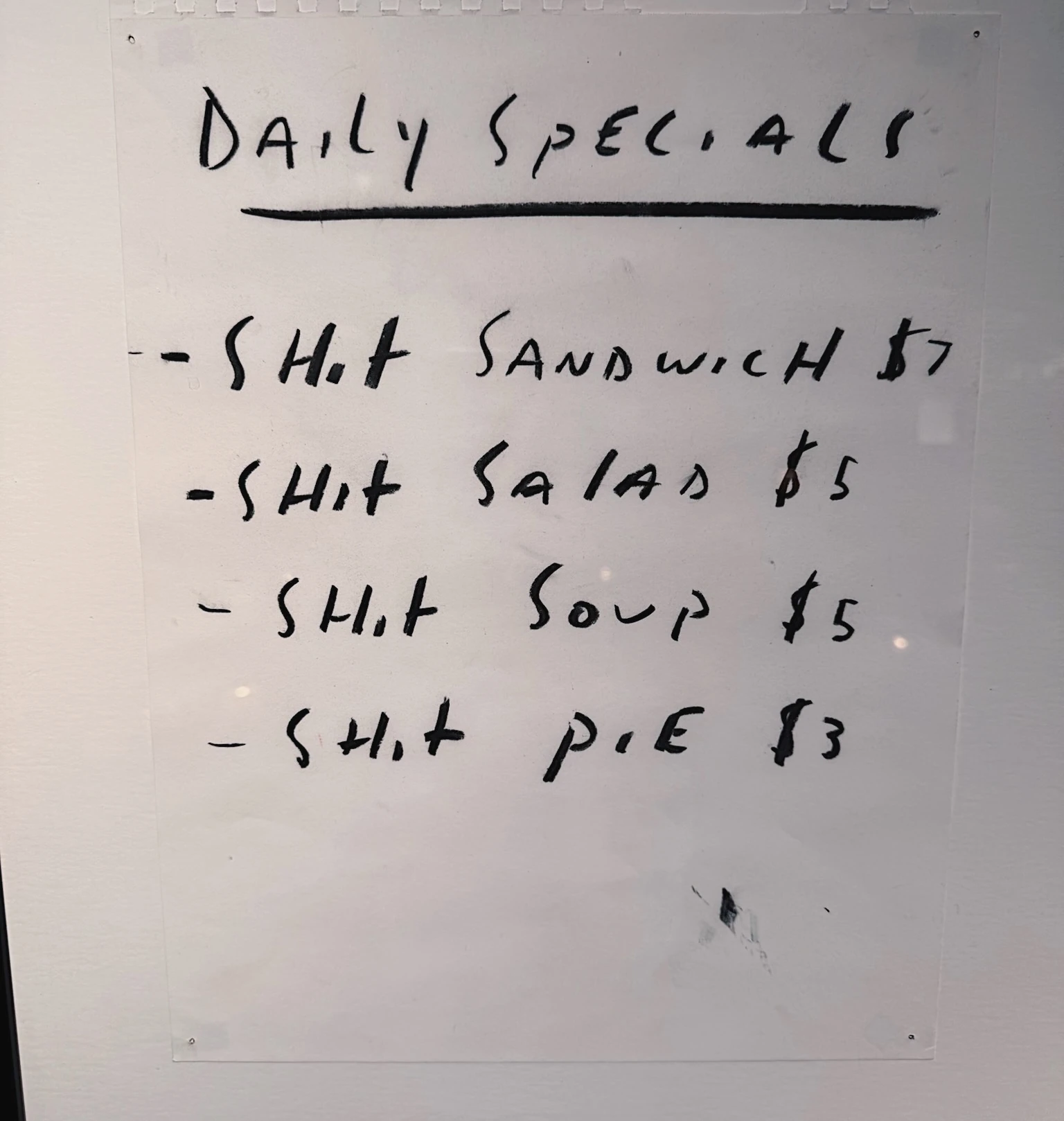 Handwritten board listing daily specials including sandwiches, salads, soup and pie