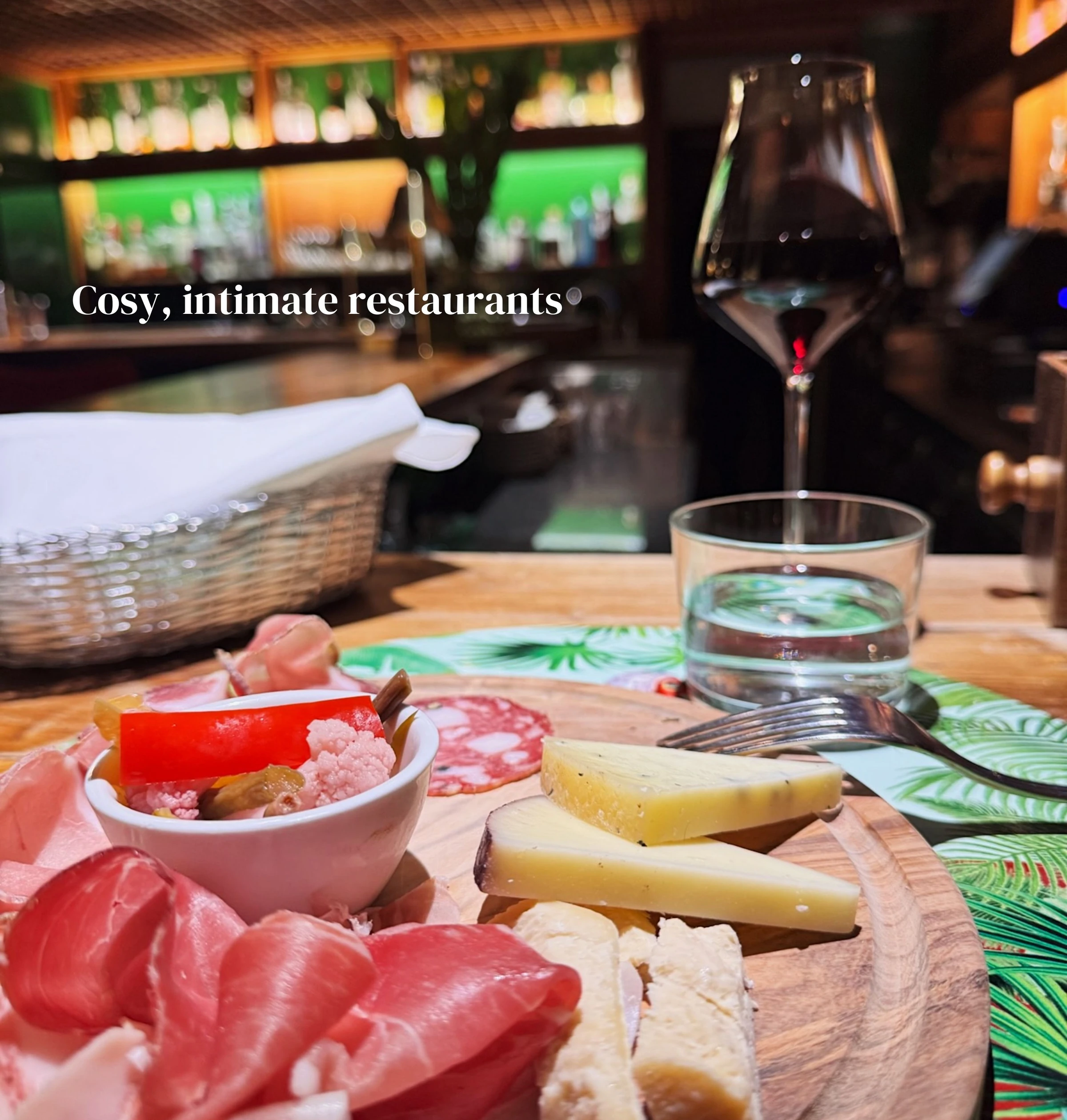 Charcuterie and cheese board beside a wine glass in a cosy restaurant