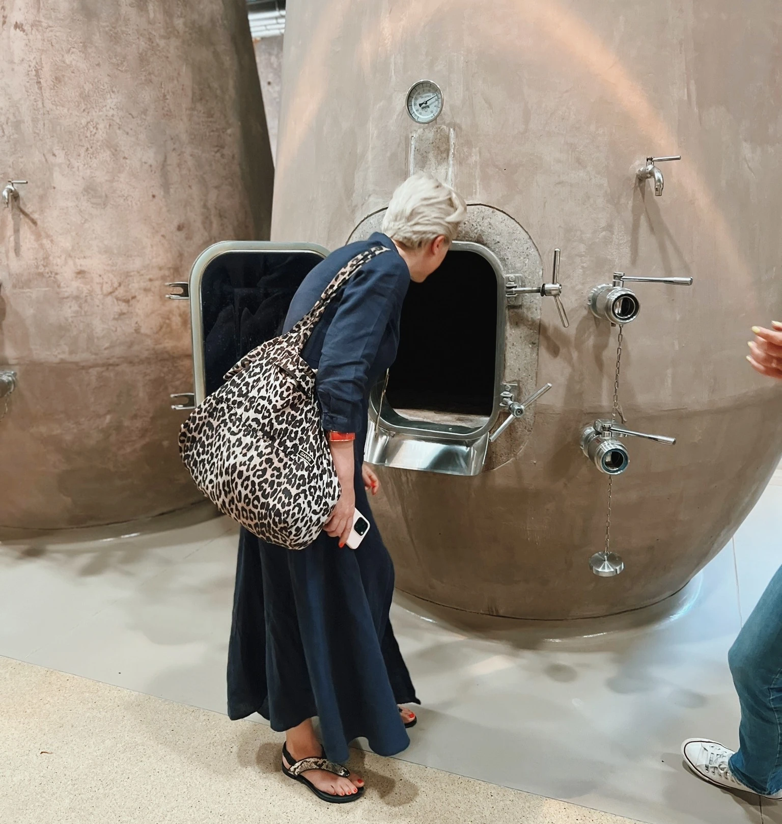 Visitor inspecting a large stainless steel tank in a winery