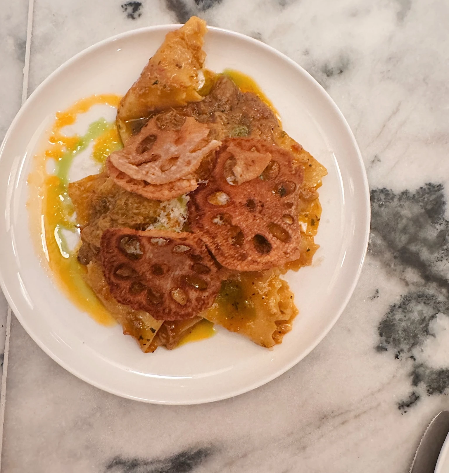 Plated savoury dish topped with crisp vegetables and served with colourful sauces