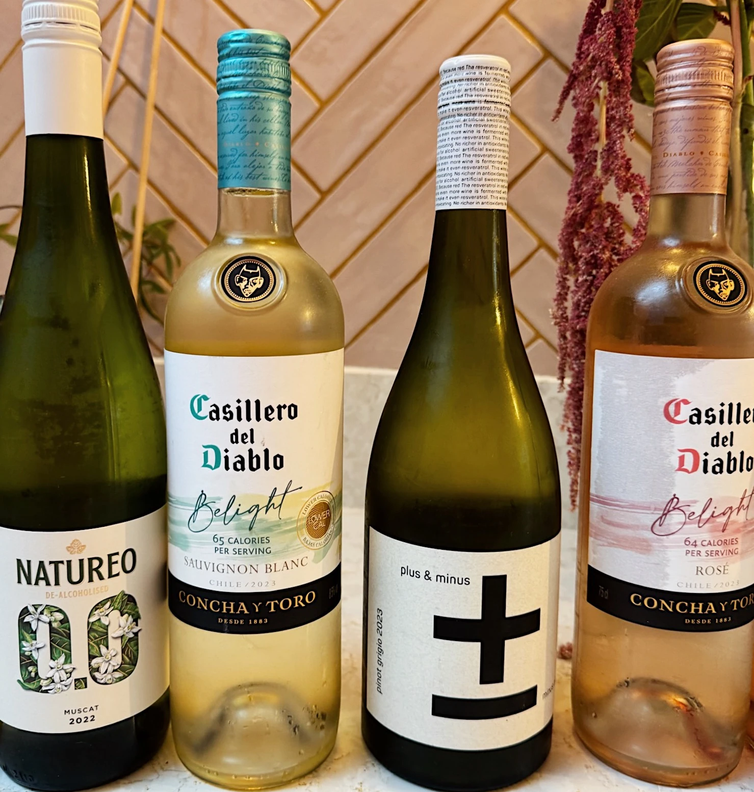 Four bottles of alcohol-free and lower-calorie wine displayed on a marble surface
