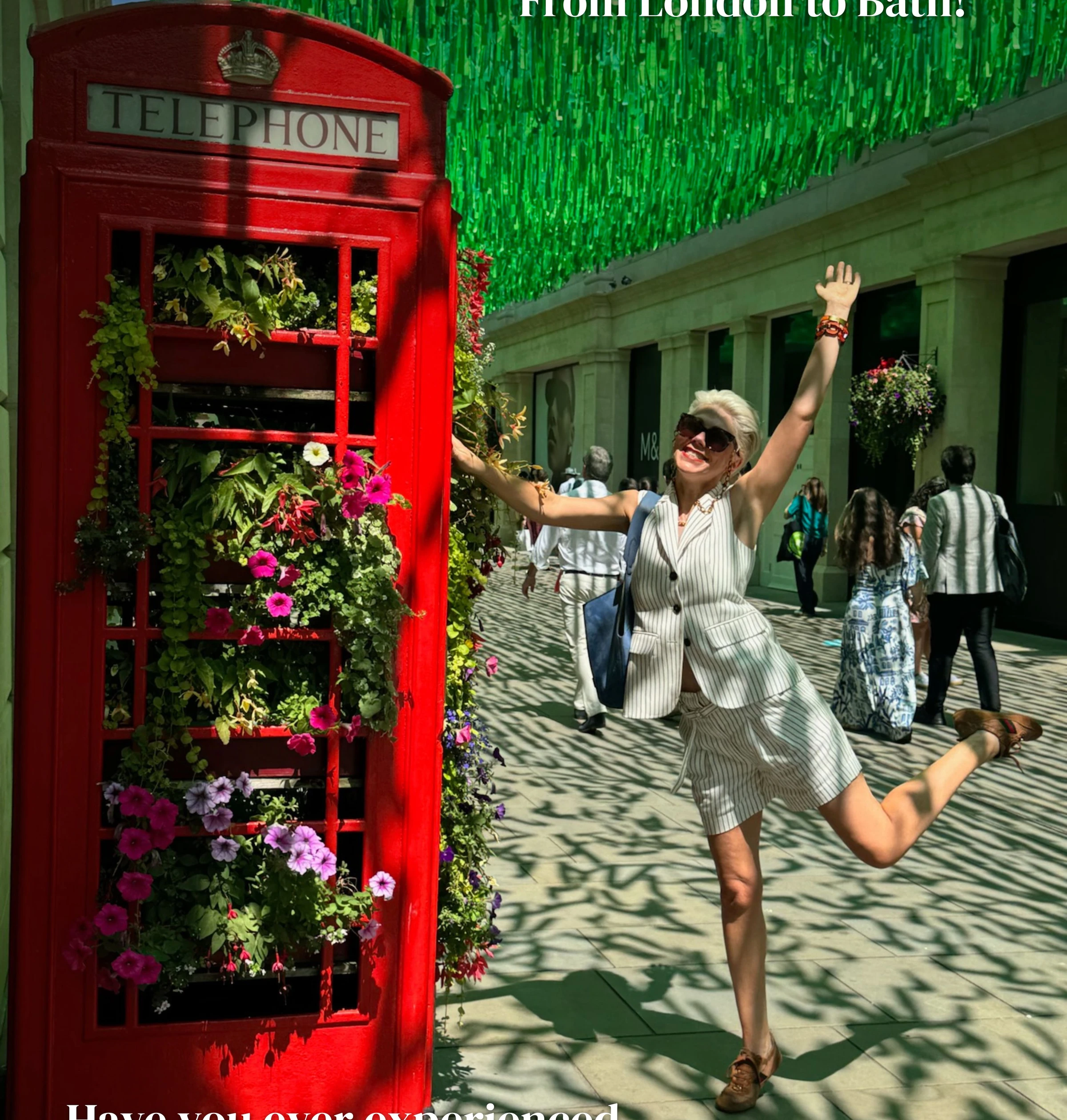 Woman posing beside a flower-filled red telephone box beneath green decorations