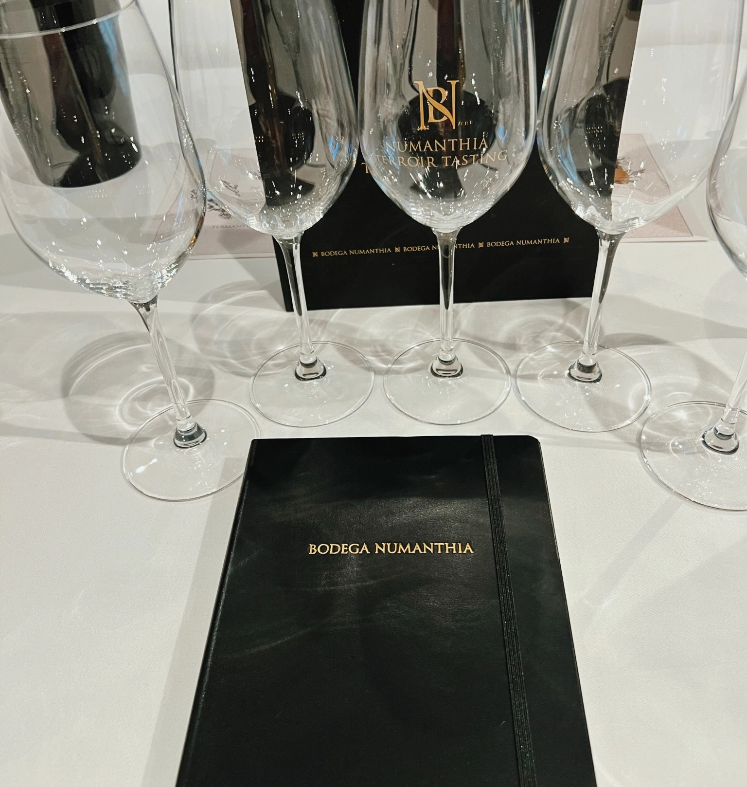 Wine glasses and a Bodega Numanthia tasting notebook on a white table