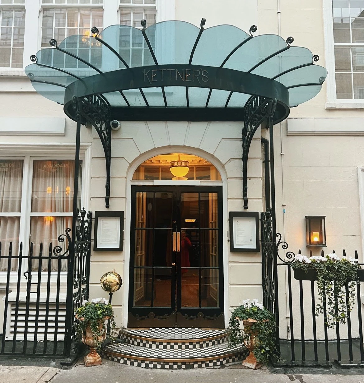 Kettner’s Champagne Bar entrance, with a glass canopy, tiled steps and flower planters.