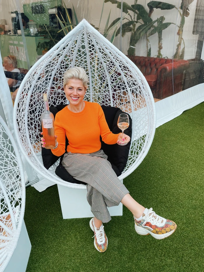 Woman holding rosé wine in hanging chair outdoors