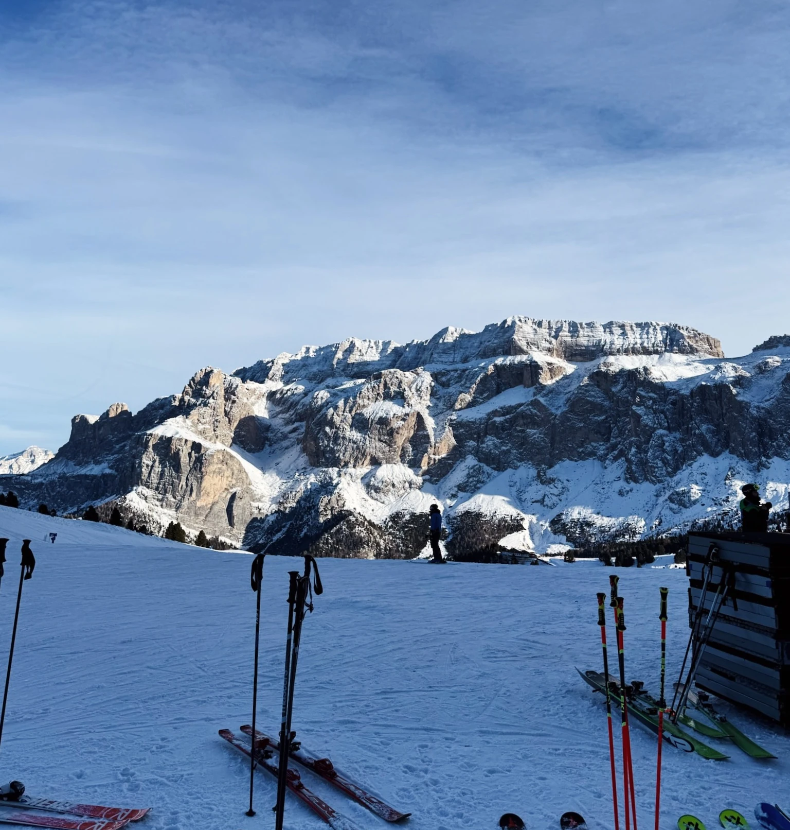 Snow-covered mountain above a ski slope with skis and poles in the foreground