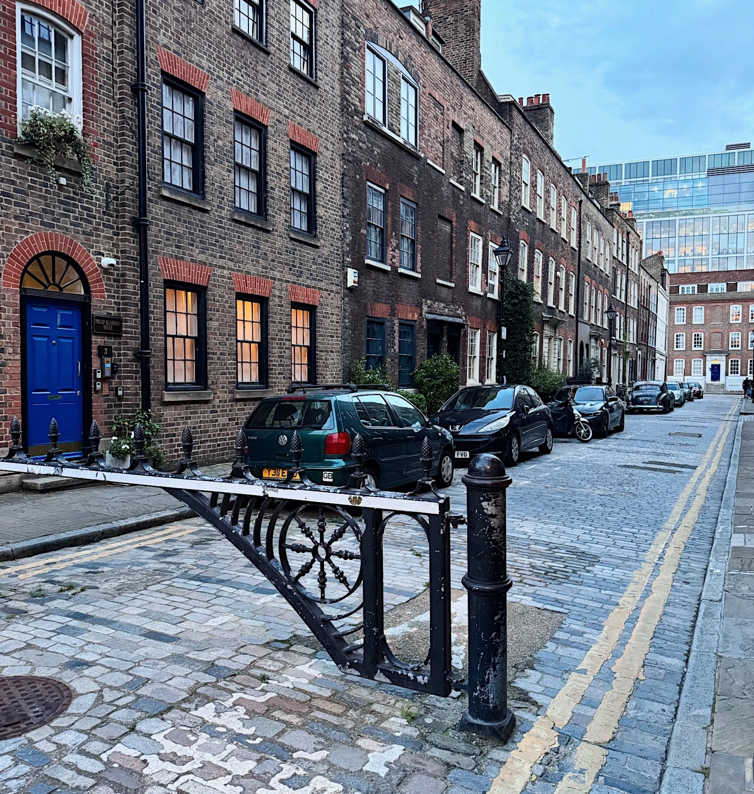 Historic brick townhouses and parked cars on a cobbled London street