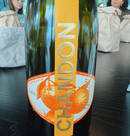Close-up of a Chandon Garden Spritz bottle with two women seated behind it
