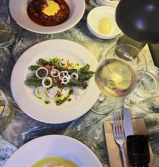 Restaurant table with asparagus, stew, oysters, wine and other dishes