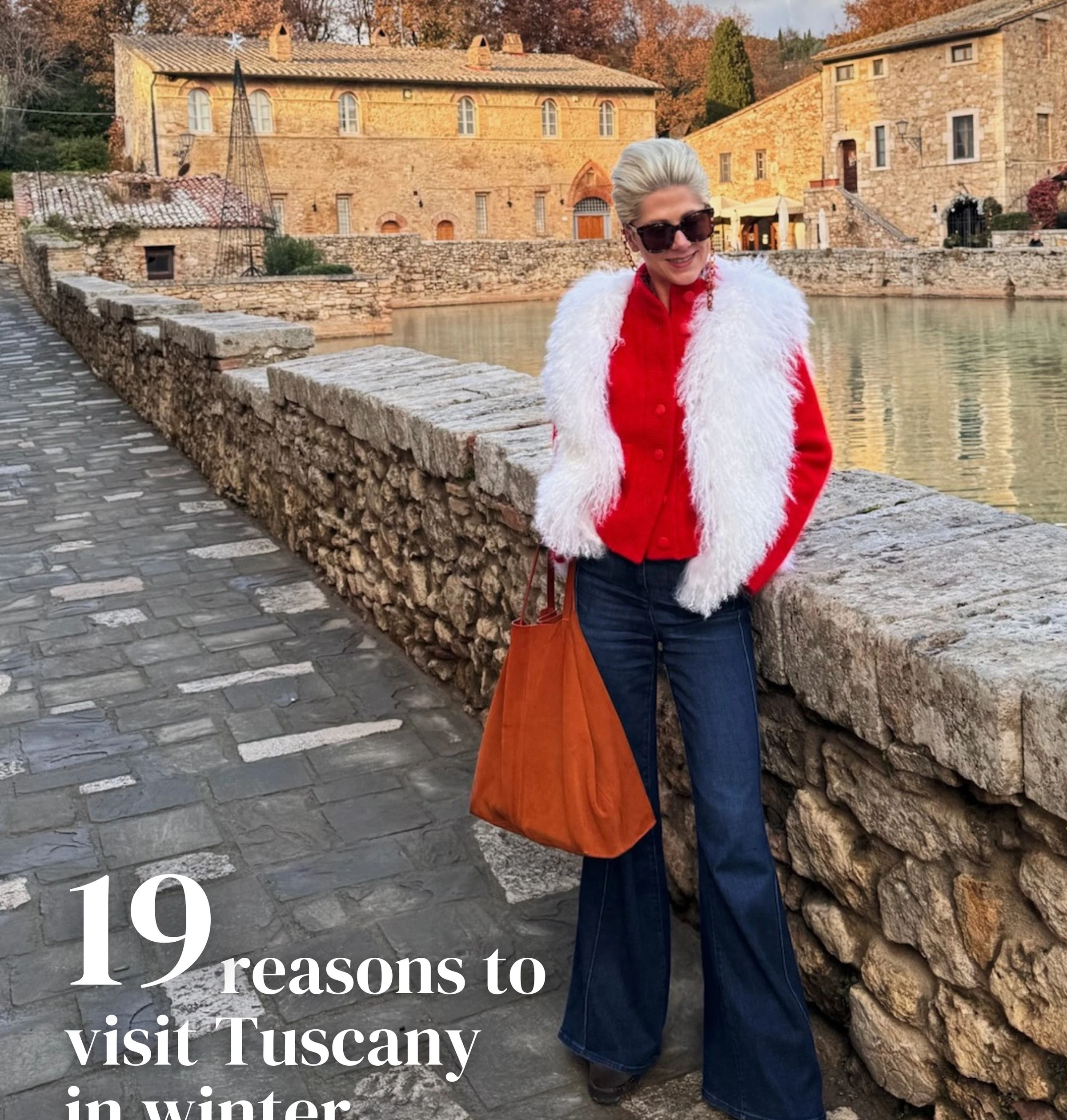 Person in a red jacket beside a stone canal in Tuscany