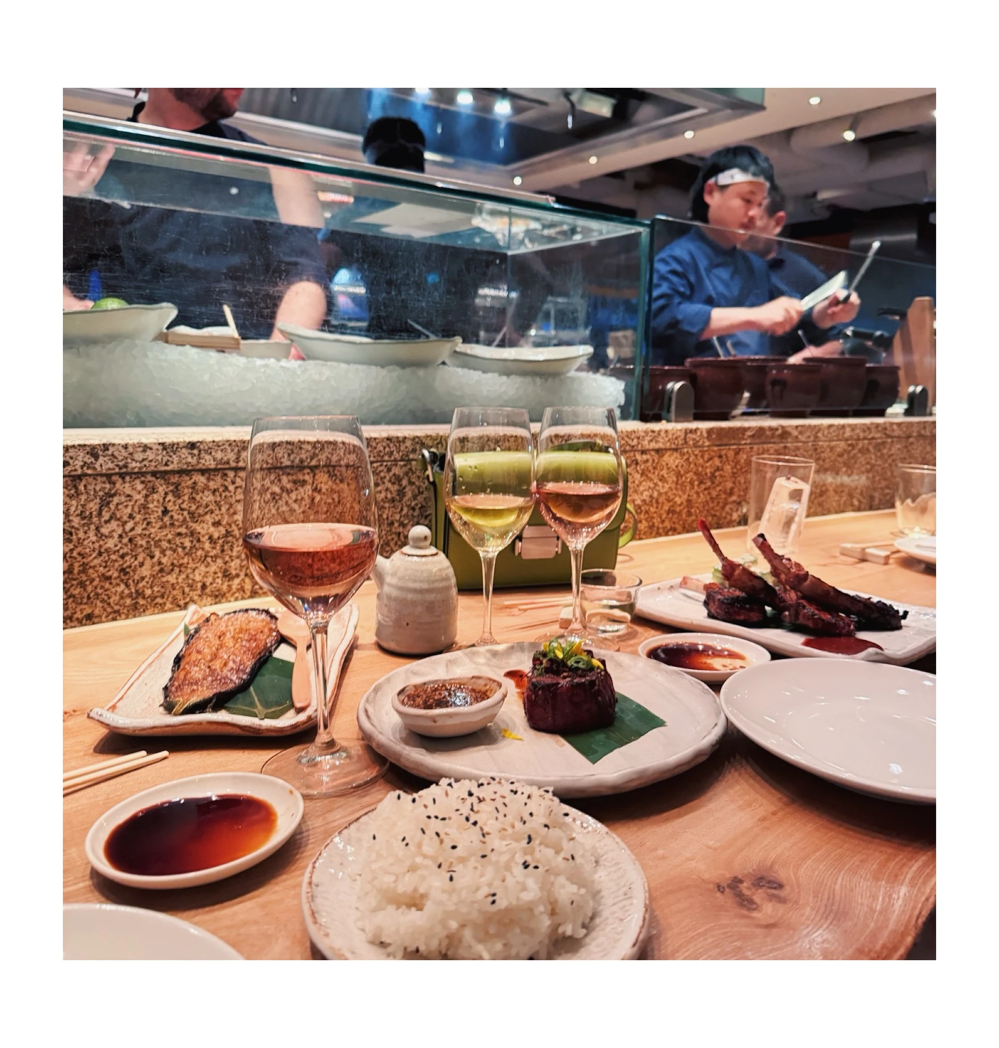 Three glasses of wine and a Japanese meal at a restaurant counter