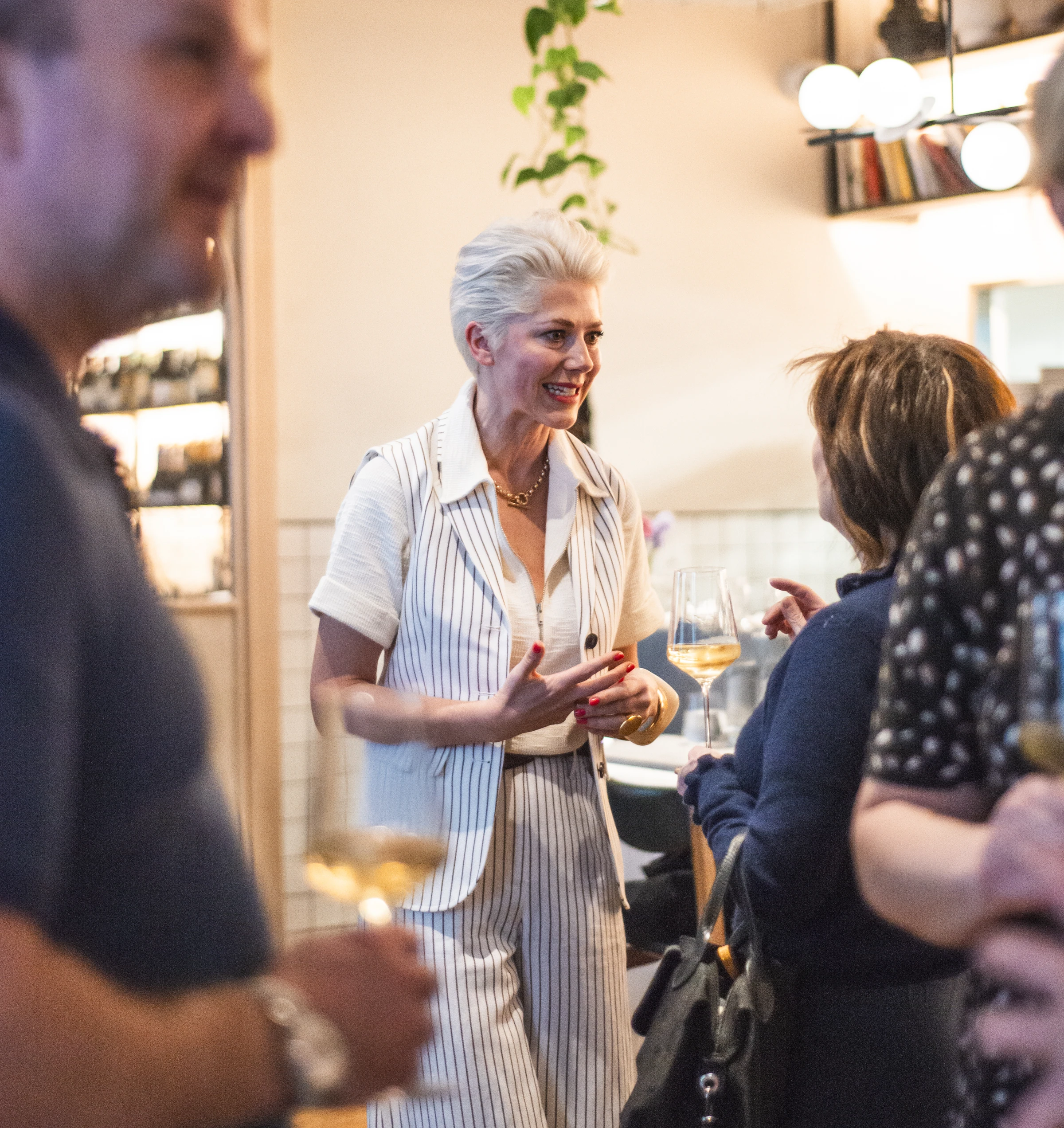Wine tasting host speaking with guests in a stylish restaurant, with glasses of white wine nearby