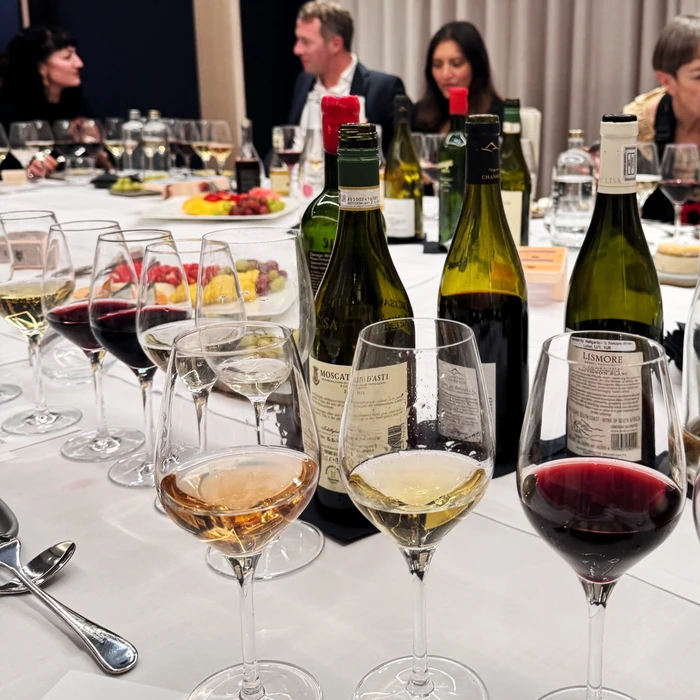 Wine tasting table with bottles, glasses and guests seated in background