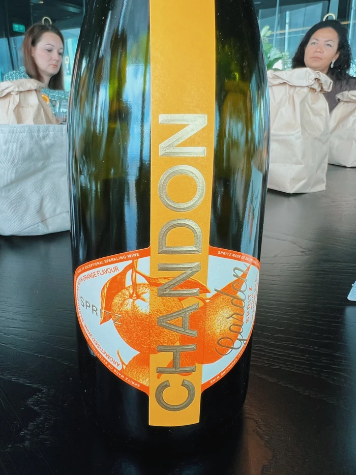 Close-up of a Chandon Garden Spritz bottle with two women seated behind it