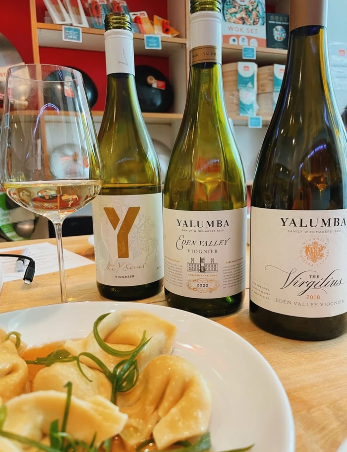 Three Yalumba Viognier bottles, a wine glass and dumplings on a restaurant table