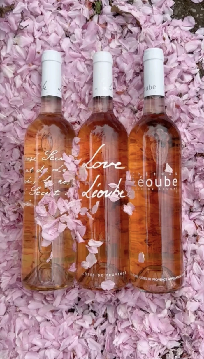 Three bottles of rosé wine surrounded by pink flower petals