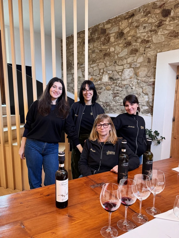 Four women pose behind bottles of Brunello di Montalcino and red wine glasses