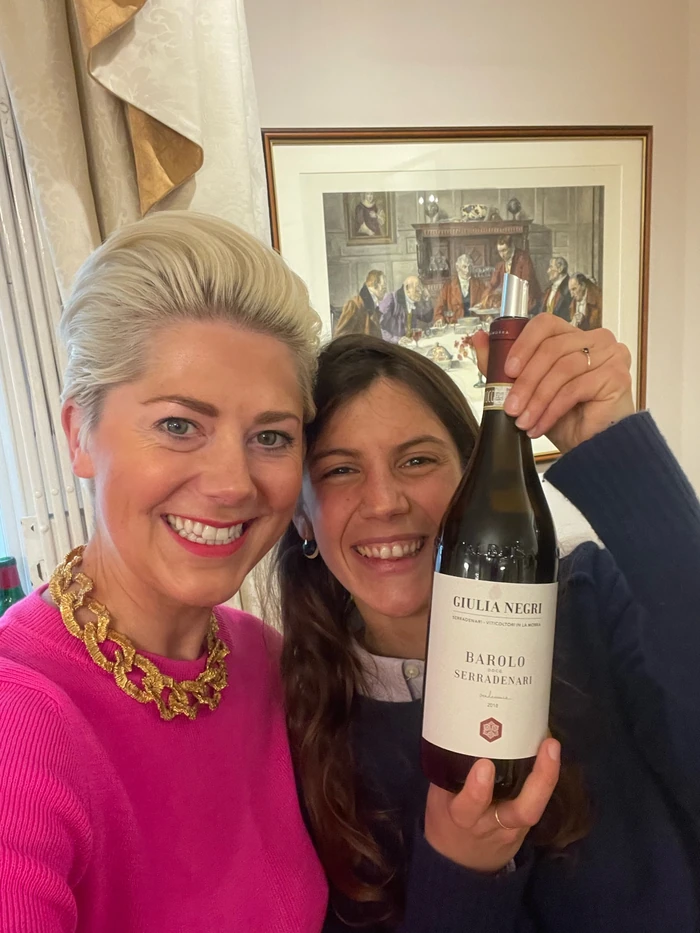 Two smiling women hold up a bottle of Giulia Negri Barolo Serradenari