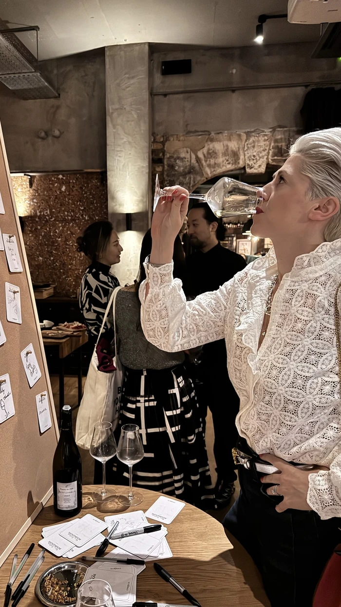Guests taste wine at a Chablis event beside a tasting table
