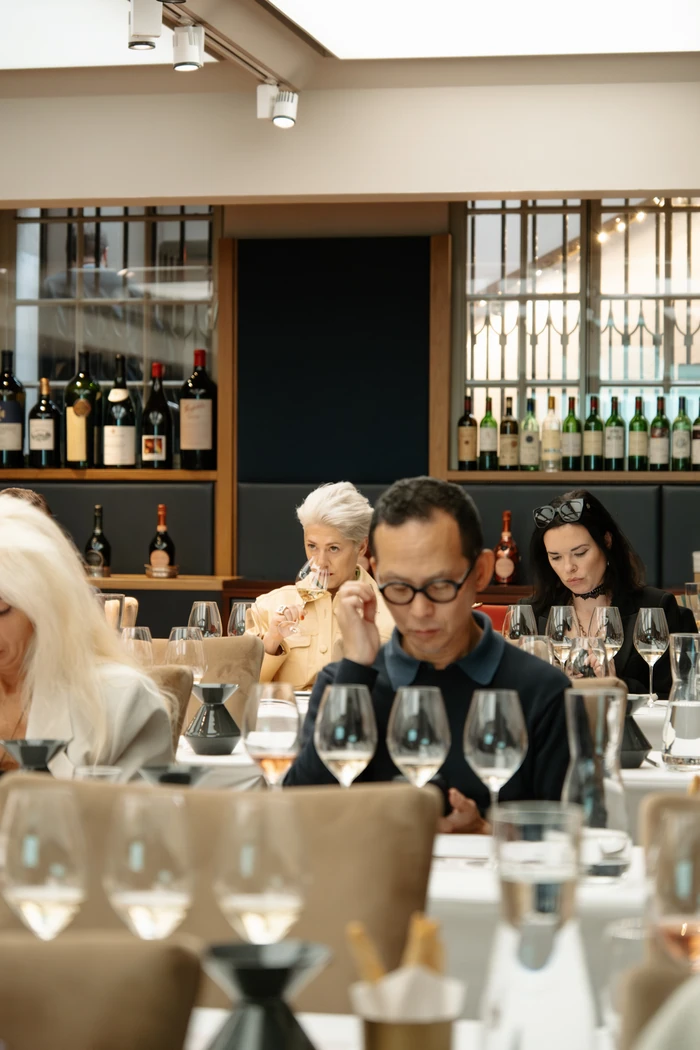 Guests taste wine around a table filled with glasses in a stylish restaurant