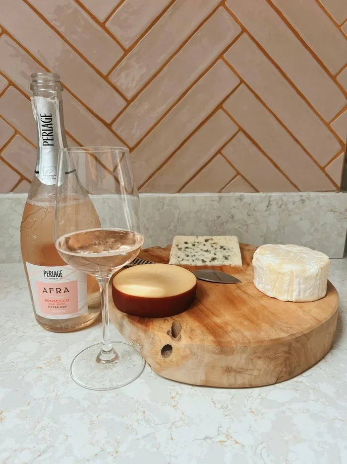 Perlage Afra Prosecco rosé with a filled glass and cheeses on a wooden board