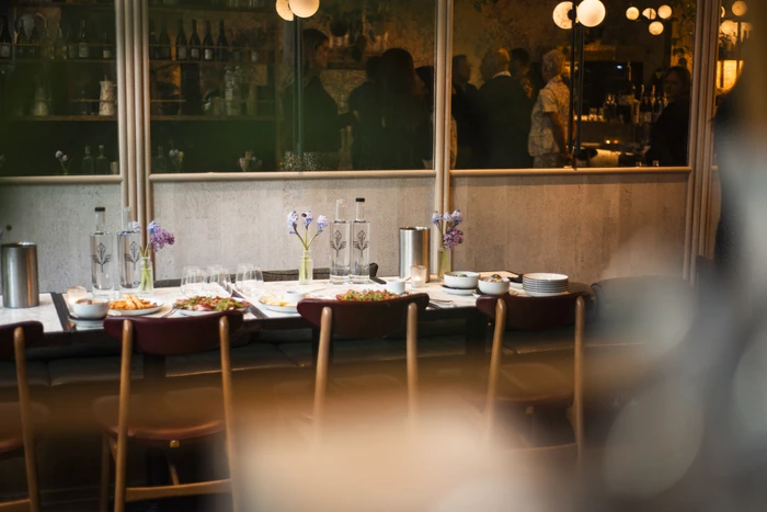 Wine tasting table set with bottles, glasses, food and flowers in a warmly lit restaurant
