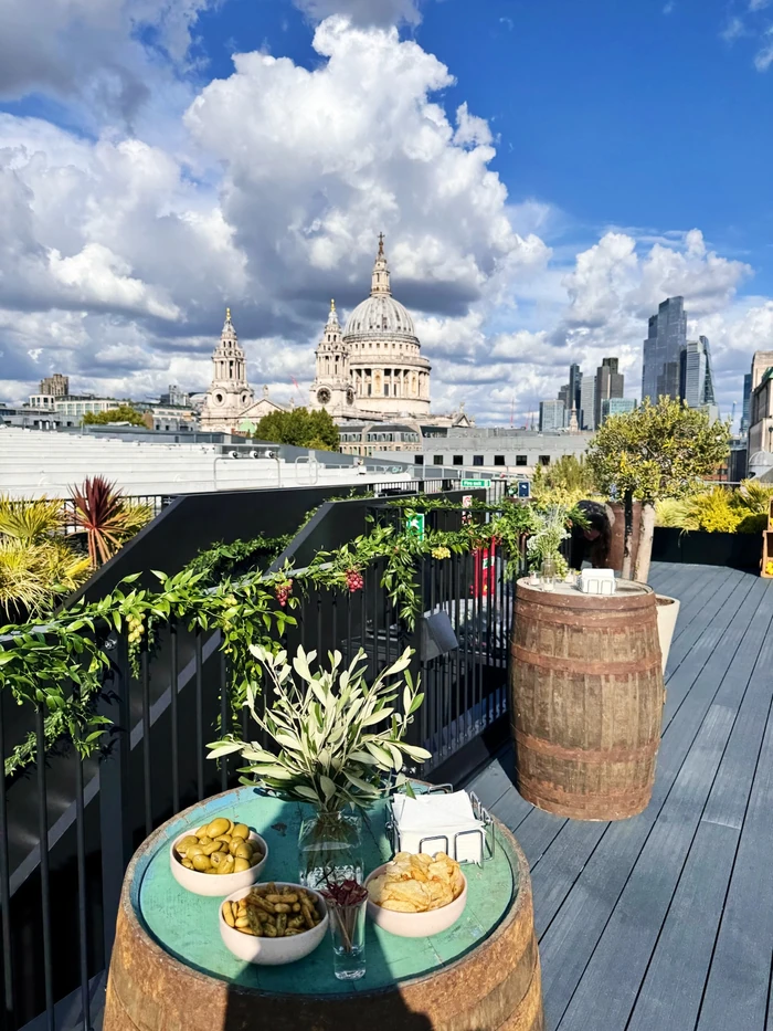 Rooftop drinks table with snacks and greenery overlooking St Paul's Cathedral and the City of London