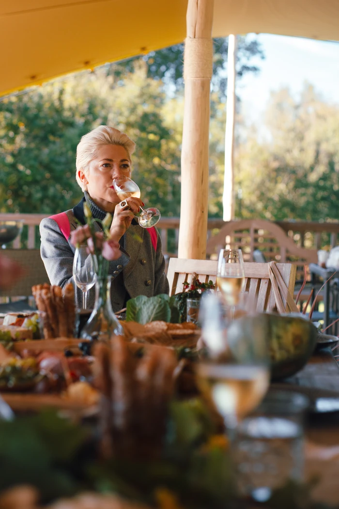 Person tasting white wine at a table on a covered terrace