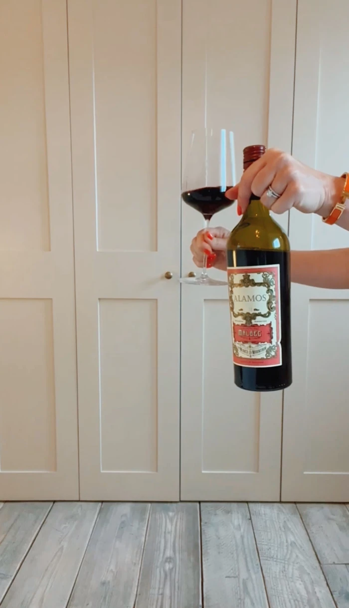Alamos Malbec bottle held beside a glass of red wine