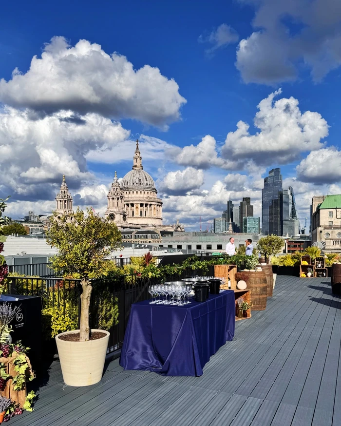 Rooftop wine tasting setup with glasses, plants and views of St Paul's Cathedral and London's skyline
