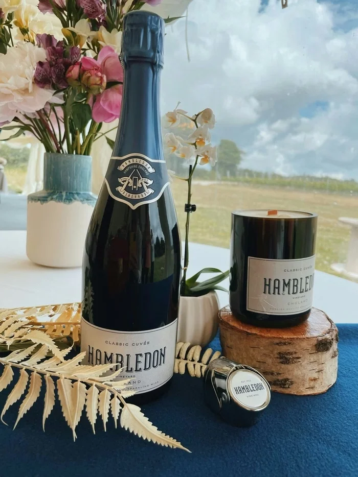 Hambledon Vineyard sparkling wine bottle and candle beside flowers by a window