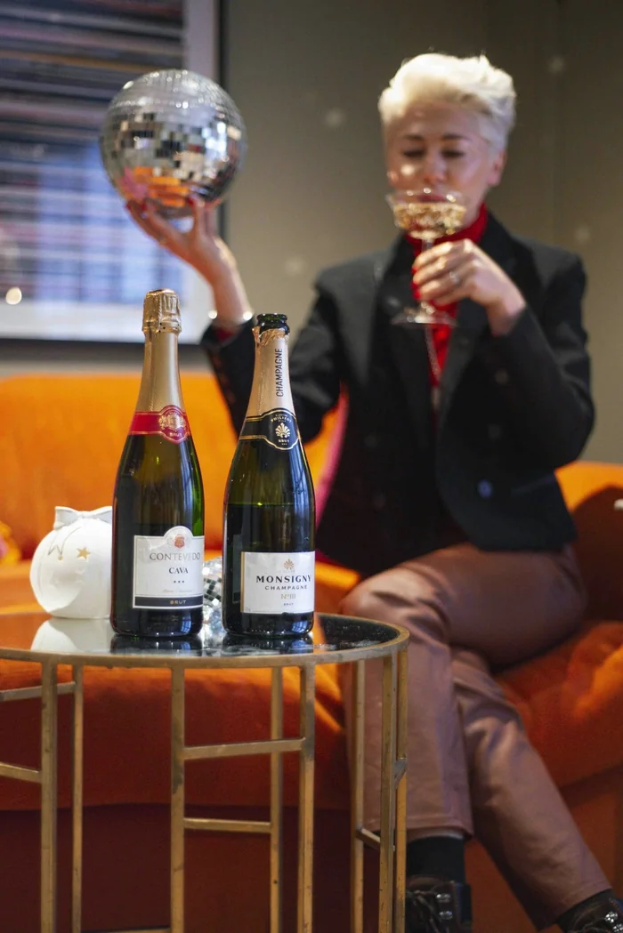 Guest raises a disco ball while tasting sparkling wine beside two bottles