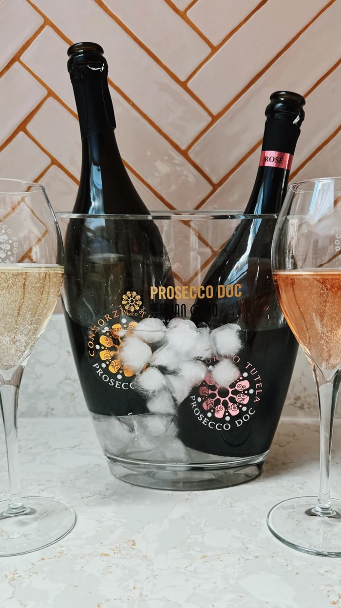 Two bottles of Prosecco DOC in an ice bucket with glasses of sparkling wine