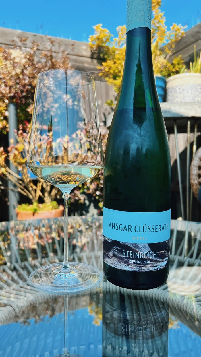 Ansgar Clüsserath Steinreich Riesling bottle beside a glass of white wine outdoors