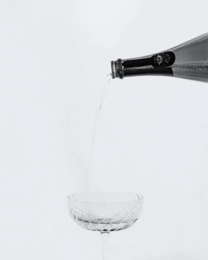 Sparkling wine being poured into a cut-glass coupe