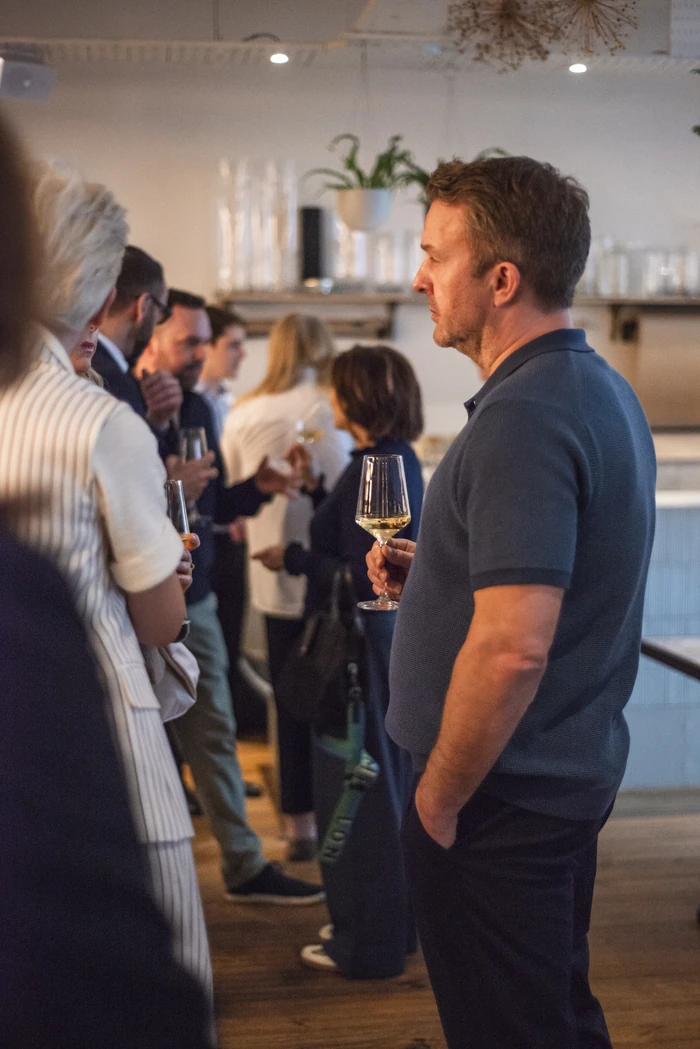 Guests mingle with wine glasses during a tasting in a stylish indoor venue