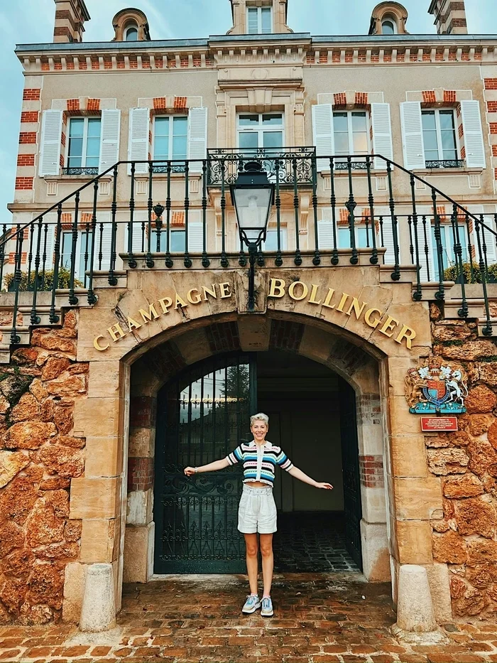 Person standing outside the Champagne Bollinger entrance in a striped top and white shorts