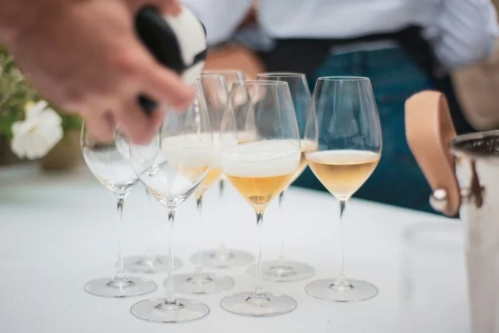Glasses of sparkling wine being poured at a tasting table