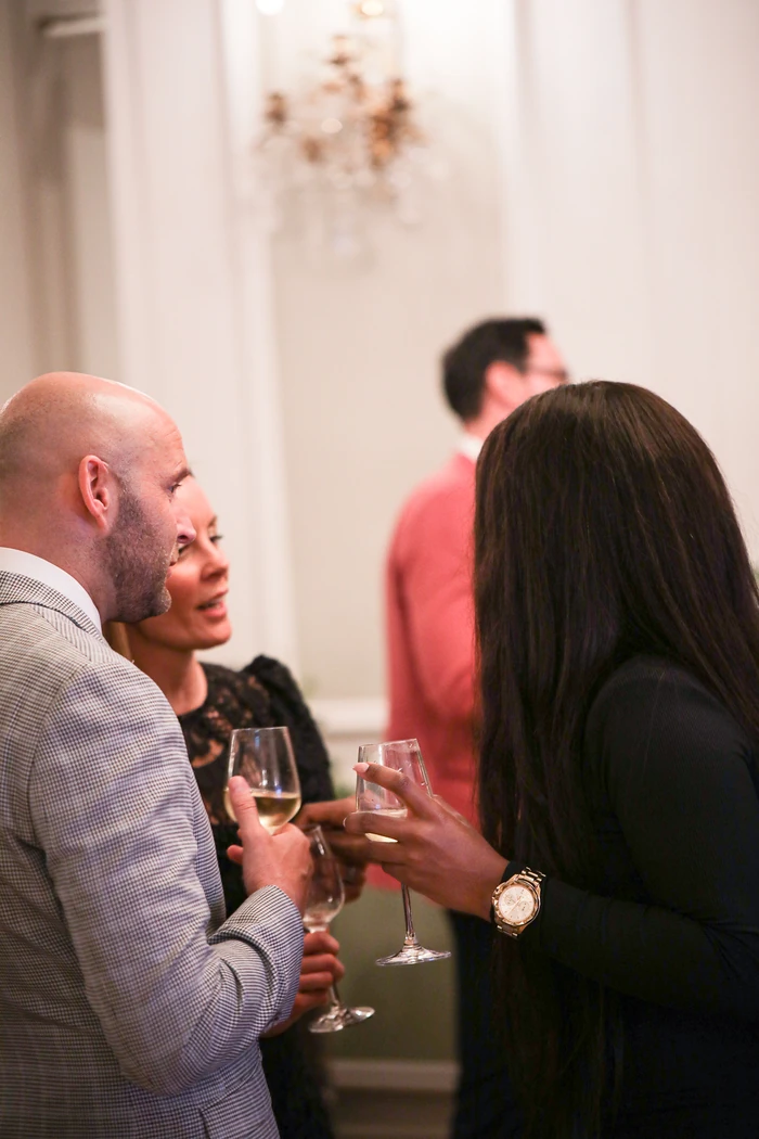 Guests chat while holding wine glasses at an indoor tasting
