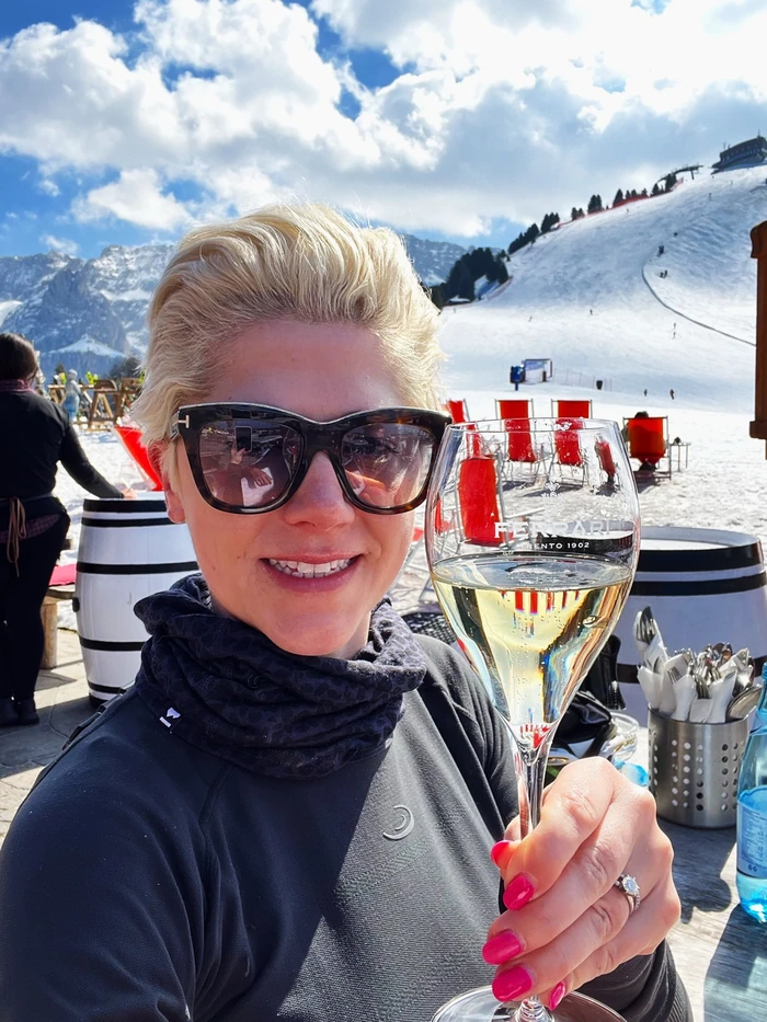 Person holding a glass of Ferrari sparkling wine at a snowy mountain resort