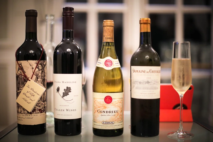 Four wine bottles and a filled wine glass arranged on a table