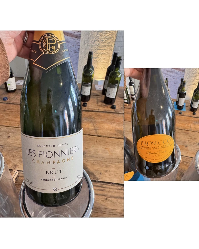 Les Pionniers Champagne bottle beside a Prosecco bottle on a tasting table