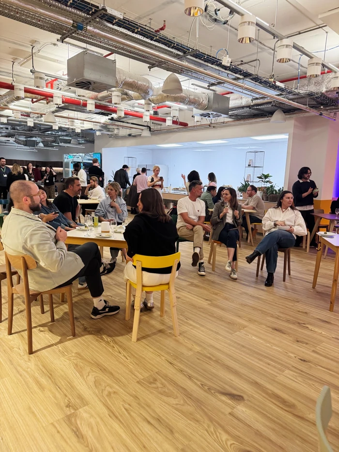 Colleagues gather around tables with wine glasses in a bright modern office space