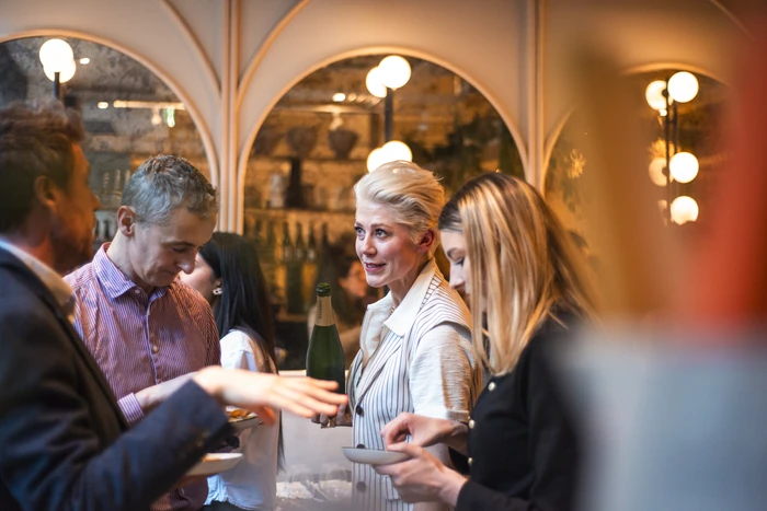 Guests mingle around a bottle of sparkling wine at a stylish indoor tasting event