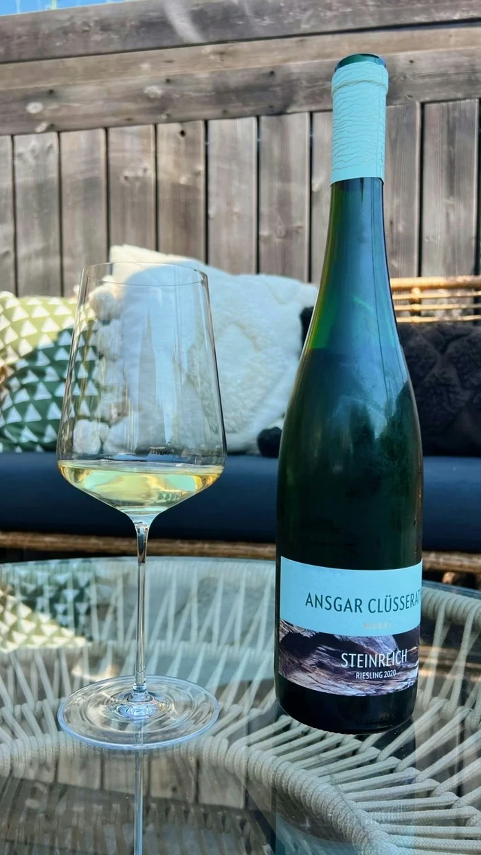 Ansgar Clüsserath Steinreich Riesling bottle beside a glass of white wine on an outdoor table