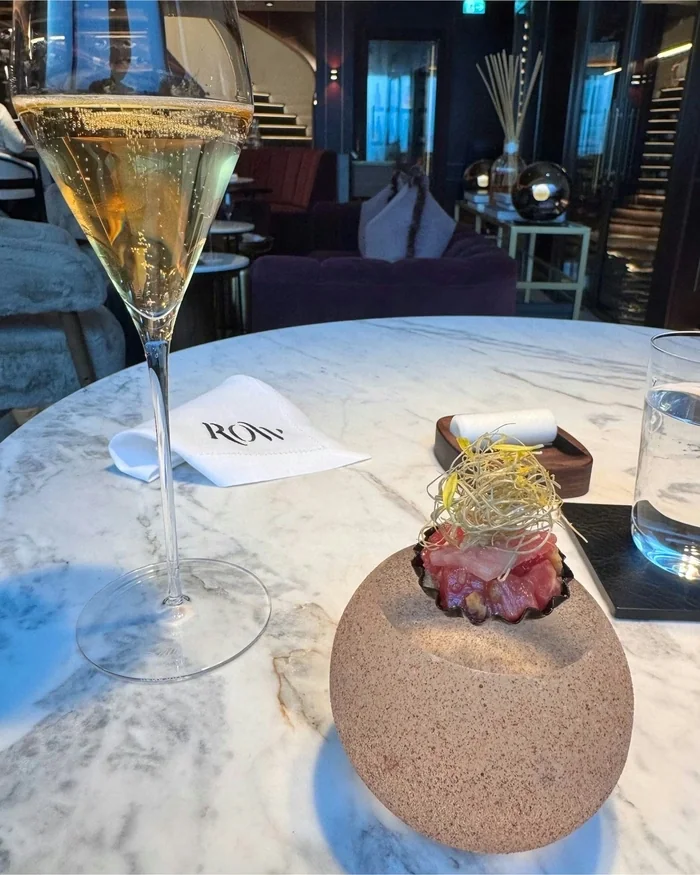 Sparkling wine and a plated appetiser on a marble table in a stylish restaurant